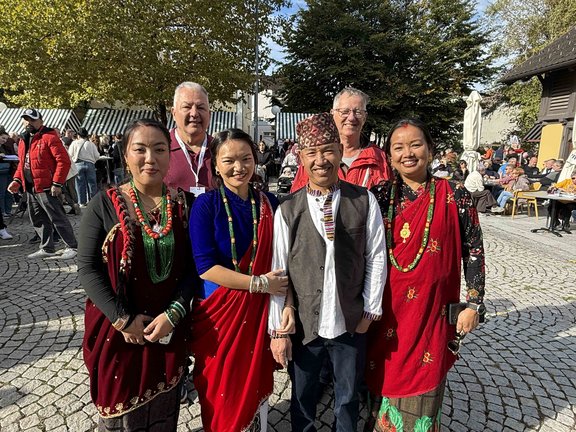 Nepal-Frauen und -Männer in traditioneller Kleidung vor einem Gebäude